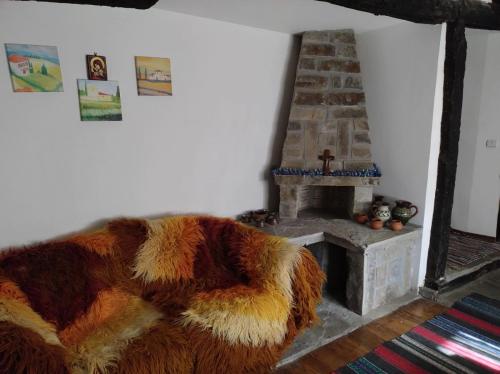 a living room with a fur couch and a fireplace at Hadjigabarevata Kashta in Dalbok-Dol