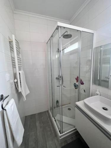 a white bathroom with a shower and a sink at Typical quiet Algarve cottage in Faro