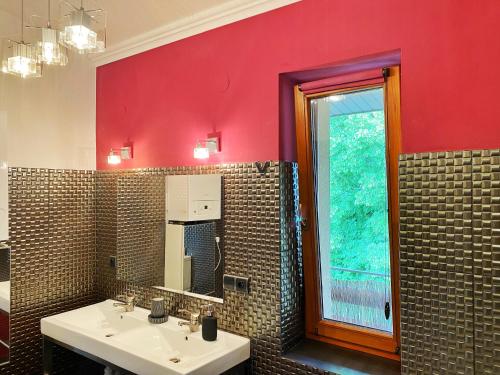baño con 2 lavabos y pared roja en Przestronny apartament z dwoma sypialniami, salonem i kuchnią, otoczony balkonem, z miejscem parkingowym 