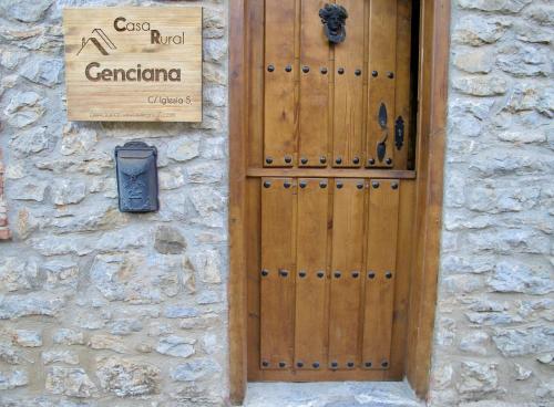 une porte en bois sur un bâtiment en pierre avec un panneau dans l'établissement Genciana, Casa Rural con encanto en La Montaña Leonesa, 