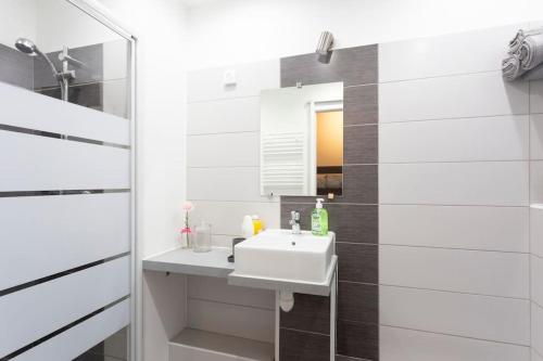 une salle de bain blanche avec un lavabo et un miroir dans l'établissement Chez Alexandra - Élégant studio avec parking à proximité des plages, à La Grande Motte