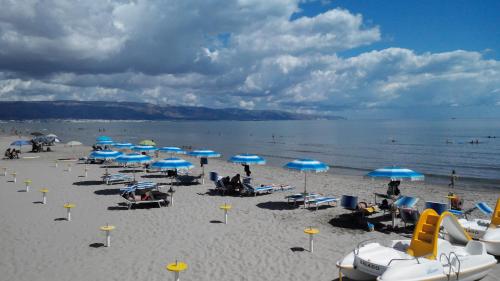 a beach with blue umbrellas and people sitting on the sand at Camping Tellina in Manfredonia