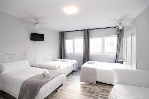 カルダス・デ・レイスにあるPensión Caldasのベッド3台、薄型テレビが備わる客室です。