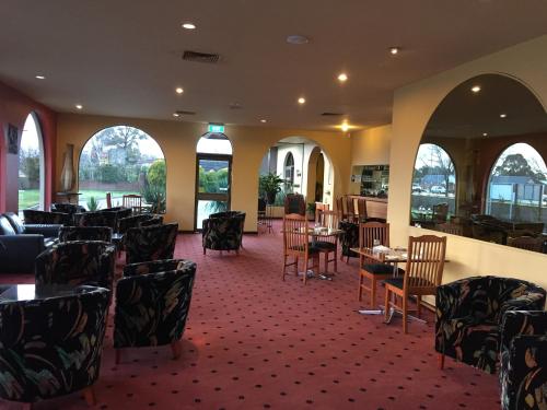 a dining room with tables and chairs and windows at Bell Tower Inn in Ballarat