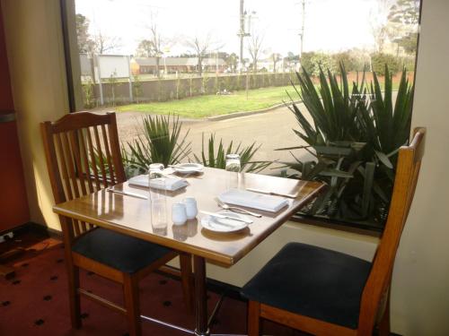 een houten tafel met 2 stoelen en een raam bij Bell Tower Inn in Ballarat