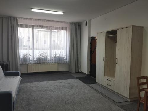 a living room with a cabinet and a large window at Apartament dla par in Olesno
