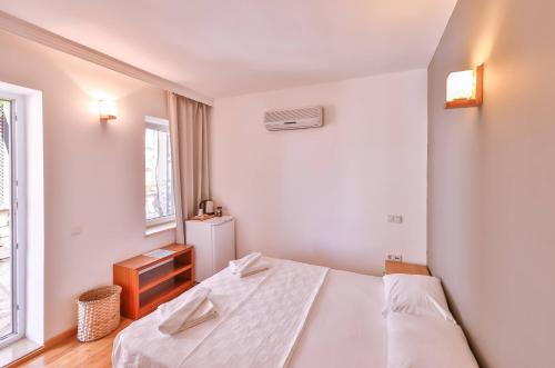 a white bedroom with a bed and a window at Luna Kaş in Kas