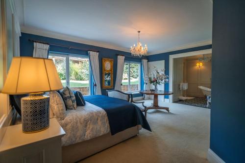 1 dormitorio con paredes azules y 1 cama con lámpara en Luxury Lodge Tinakilly, en Wicklow