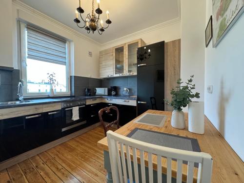 a kitchen with a wooden table and black cabinets at Ferienwohnung Coco Brockesstr. 10 in Lübeck