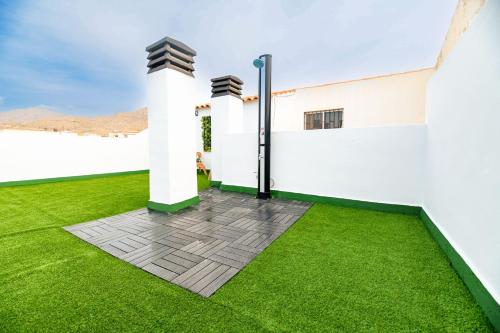 a garden with green grass and white walls at The Beach -Villa Mar- in Bolnuevo