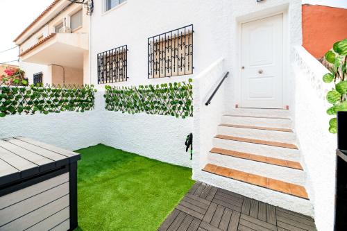 a courtyard with green grass and a white door at The Beach -Villa Mar- in Bolnuevo