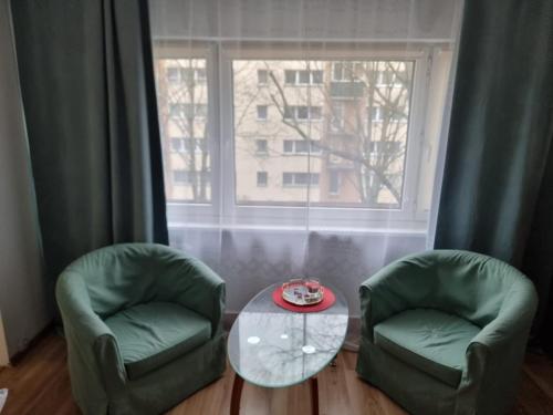 uma sala de estar com duas cadeiras, uma mesa e uma janela em Mieszkanie ul. Pustola em Varsóvia