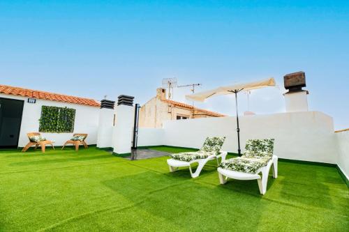 a patio with grass and chairs and an umbrella at The Beach -Villa Mar- in Bolnuevo