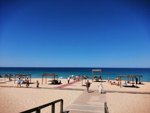 un gruppo di persone che camminano sulla spiaggia di Casa do Largo ad Alcácer do Sal