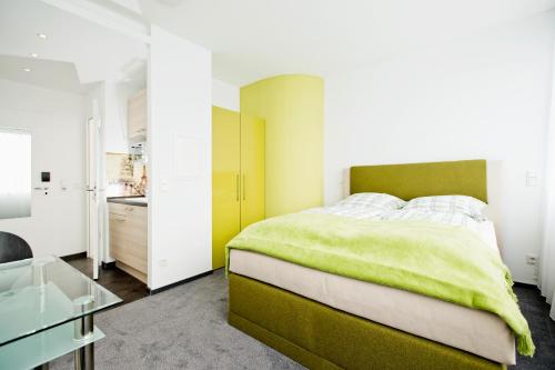 Un dormitorio con una cama verde y una mesa de cristal en Design Sleepy Cologne, en Colonia