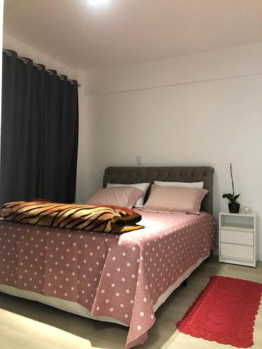 a bedroom with a bed with pink and white polka dots at Ap no centro com ar condicionado e Garagem Coberta in Cascavel