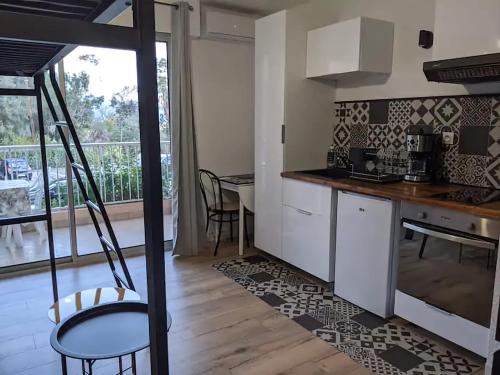 une cuisine avec des armoires blanches et une table dans l'établissement Studio 4 pers terrasse vue mer, à Ajaccio