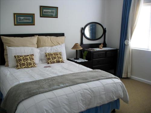 a bedroom with a bed with a mirror and a dresser at Belcharto Accommodation in Stellenbosch