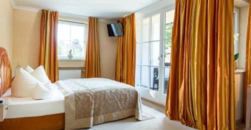 a bedroom with a bed and a window with orange curtains at Alpenhof in Bayrischzell