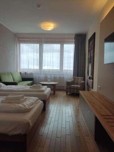 a hotel room with two beds and a couch at Hotel Madl in Velké Bílovice