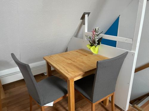 uma mesa de jantar com duas cadeiras e um vaso com flores em HN Citywohnung Klein aber nur für mich! em Heilbronn