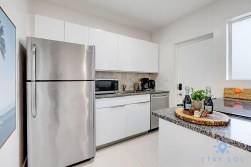 a kitchen with white cabinets and a stainless steel refrigerator at Free Parking - Bay View - Pool - Step To Beach in Hollywood