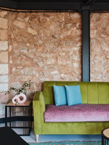 a green couch sitting in a room with a brick wall at Not Boutique Hotel in Athens