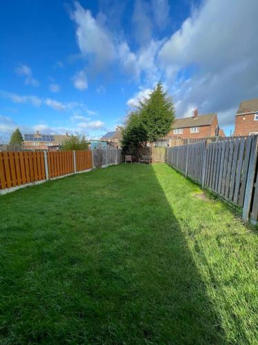 a backyard with a fence and green grass at Stunning 3 bedrooms house with Garden and Free Parking in Barnsley