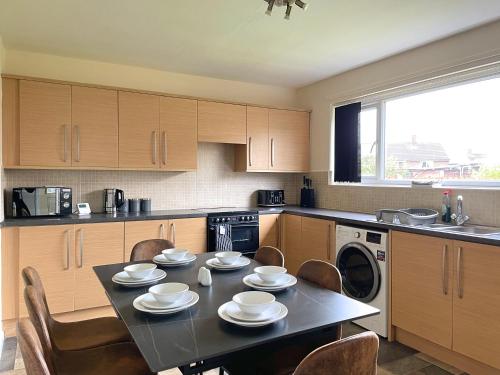 a kitchen with a table and chairs and a table and a dishwasher at Stunning 3 bedrooms house with Garden and Free Parking in Barnsley