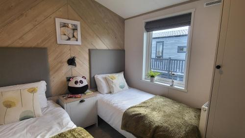 ein kleines Schlafzimmer mit 2 Betten und einem Fenster in der Unterkunft Honeycomb Lodge - Holiday Home 5 min from Padstow in Padstow