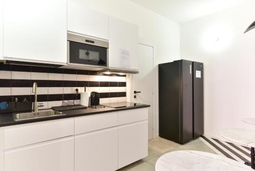 a kitchen with white cabinets and a black refrigerator at FanfullArt in Rome