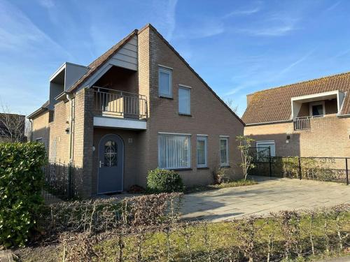 a brick house with a balcony and a fence at Crox Houcke 24* in Nieuwvliet