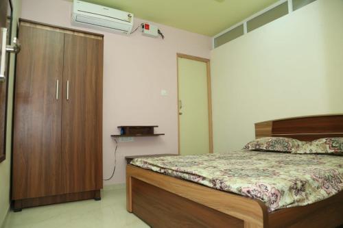 a bedroom with a bed and a wooden cabinet at PARADISE BANQUET HALL & A/C ROOMS in Madurai