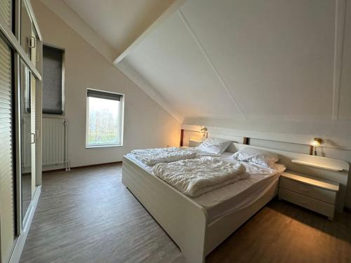 a bedroom with a large white bed and a window at Crox Houcke 24* in Nieuwvliet