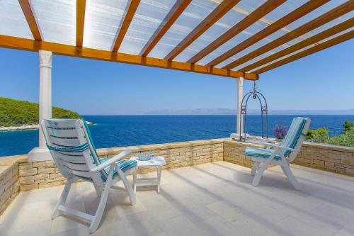 2 sillas y una mesa en un patio con vistas al océano en STONE VILLAGE, en Vela Luka