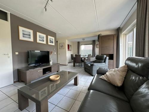 a living room with a black leather couch and a television at Crox Houcke 24* in Nieuwvliet