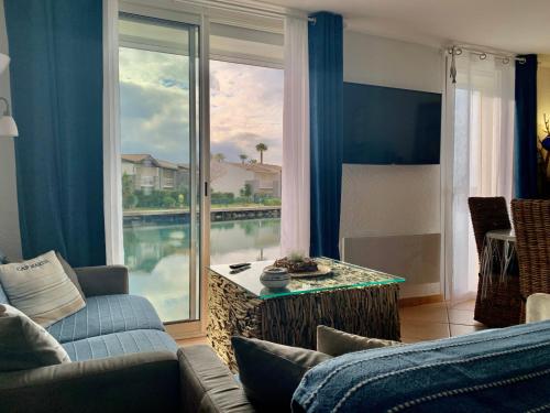 uma sala de estar com um sofá e uma grande janela em Appartement Vue Mer - RDC - Parking Privé - Meublé Tourisme 4 étoiles em Cap d'Agde