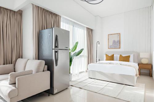 a white bedroom with a refrigerator and a bed at Silkhaus Vacation Homes Luxury Studio in Residential Neighborhood in Dubai