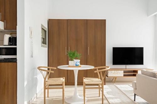 a living room with a table and chairs and a tv at Silkhaus Vacation Homes Luxury Studio in Residential Neighborhood in Dubai