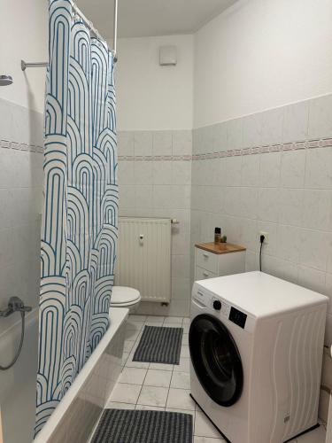 een wasmachine in een badkamer met een douchegordijn bij Apartment „Babylon“ in Leipzig