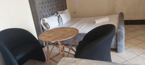 Tamara One Bedroom Apartment in Shanzu في مومباسا: سرير بطاولة وكرسيين في الغرفة