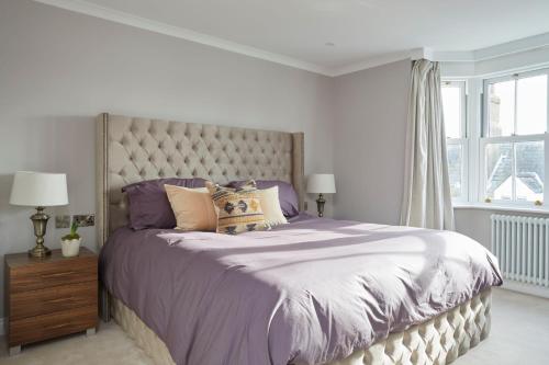 een slaapkamer met een groot bed met paarse lakens en kussens bij No41 Cowes in Cowes
