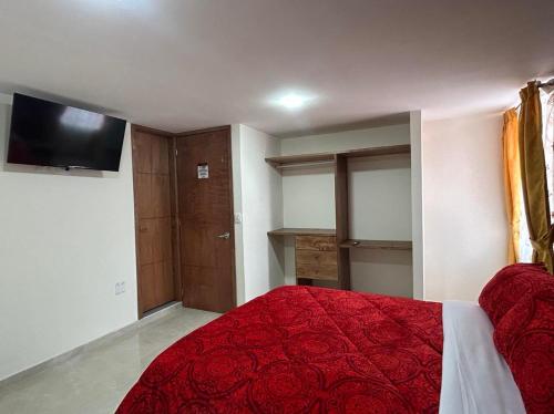 a bedroom with a red bed and a flat screen tv at Hotel Colonial House in Pasto