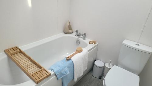 ein Badezimmer mit einer weißen Badewanne neben einem WC in der Unterkunft Honeycomb Lodge - Holiday Home 5 min from Padstow in Padstow