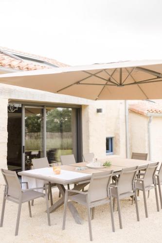 une table et des chaises blanches avec un parasol dans l'établissement La borderie de Beauregard, à Treize-Vents