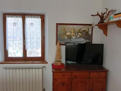 a television on a wooden dresser next to a window at Chalet Abetone in Tuscany in Abetone