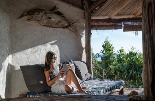 a woman sitting on a couch reading a book at Bo'a Vida Rote in Nembrala
