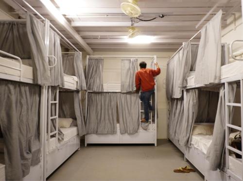 a man standing on a ladder in a room with bunk beds at Hammock Hostels - Bandra in Mumbai