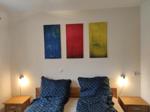 um quarto com duas camas e três pinturas na parede em Ferienwohnungen Seereif im Erdgeschoss und Seeklein im Souterrain em Immenstaad am Bodensee