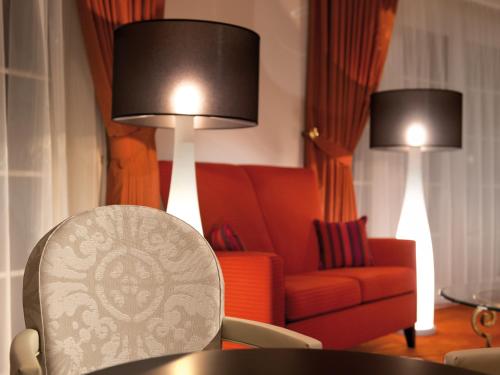 a living room with a red chair and two lamps at A-ROSA Strandidyll Heringsdorf in Heringsdorf